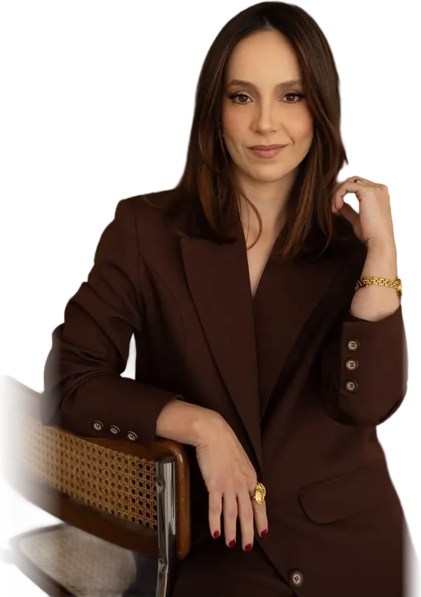 Mari Benante, advogada, de terno marrom, sentada de lado em uma cadeira de palhinha, olhando direto para quem lê.